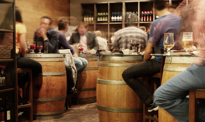 Lidé sedící v hospodě u stolů s alkoholem