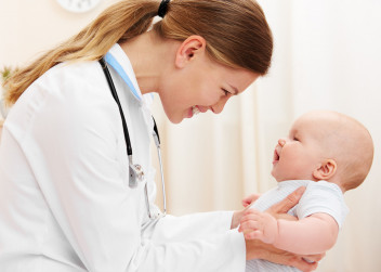 Lékařka drží v rukách usmívající se miminko